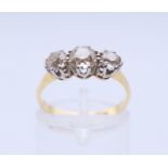 An 18 ct gold and platinum three-stone diamond ring. The central stone spreading to approximately 0.