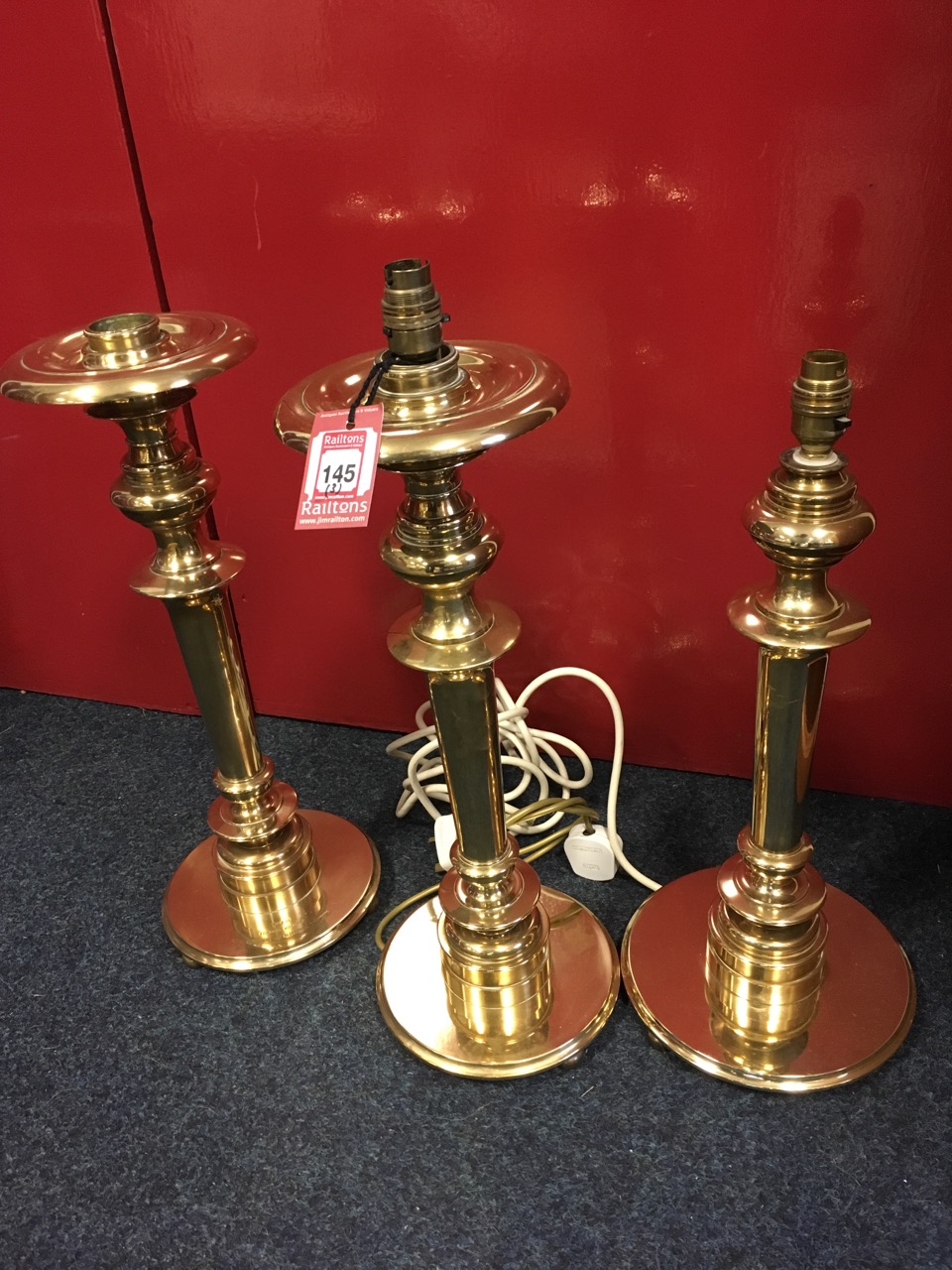 A set of three large brass candlesticks by the Command of the