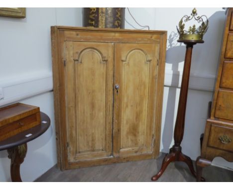 A George III pine wall hanging corner cabinet with two panelled doors with arched mouldings, opening to reveal blue painted w