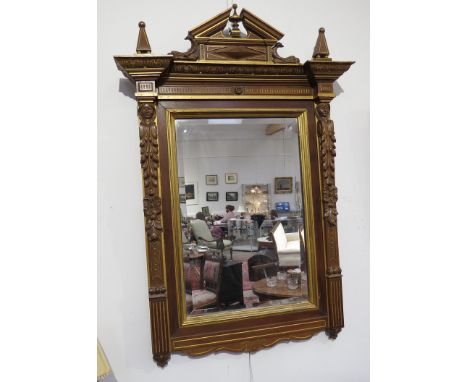 A Victorian walnut architectural form wall mirror, the broken pediment over a foliate and mask relief frame, enriched with gi