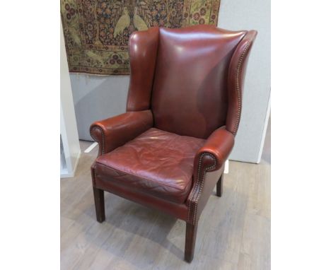 A 1940s Georgian style wingback armchair with brown leather button-back studded upholstery. Monks Hall Estate 
