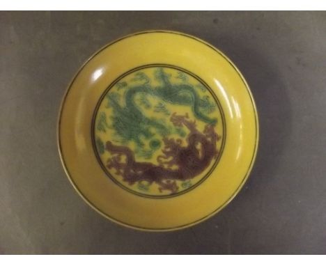 A Chinese porcelain dish decorated with dragons chasing the flaming pearl on a yellow ground, with fruiting vines verso, 6 ch