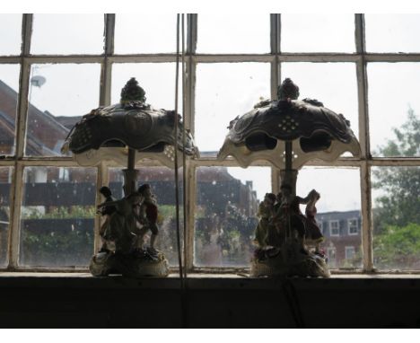 A pair of Dresden style table lamps, the ceramic shades encrusted with flowers over bases depicting dancing children, 40cm hi