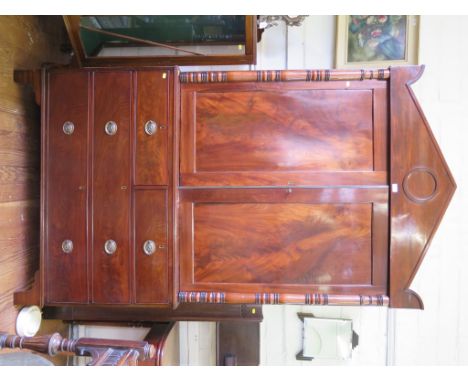 An early 19th century mahogany linen press, the triangular pediment over ring turned pilasters and panelled doors, above two 
