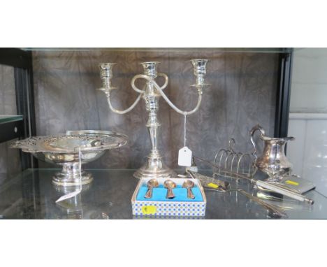 A collection of silver plate to include a swing handle basket, a two branch candelabra, a toast rack, etc