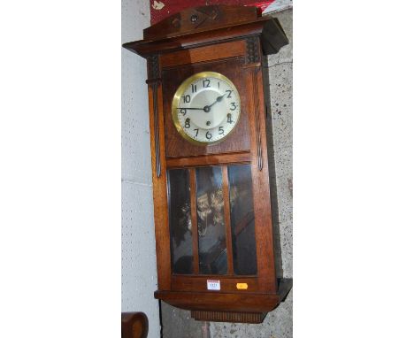 An early 20th century mahogany drop trunk wall clock, with pendulum
