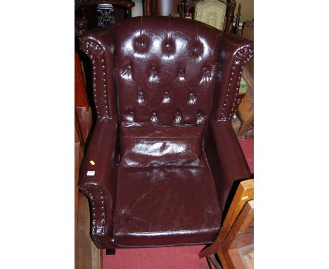 A tan leather and studded button back winged scroll armchair, width 81cm, together with a red leather buttoned and studded wi