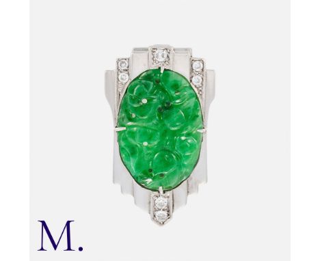 An Art Deco Jade And Diamond Clip Brooch in 14k white gold and platinum, set with a carved piece of jade accented with round 