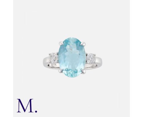An Aquamarine And Diamond Three Stone Ring in 18k white gold. Set principally with an oval cut aquamarine of approximately 4.