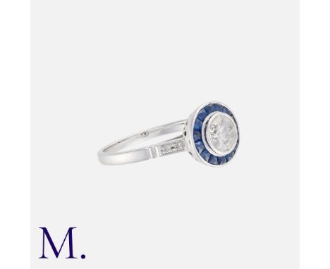 A Sapphire And Diamond Target Ring in 18k white gold set with a central round cut diamond of approximately 0.60cts within a b