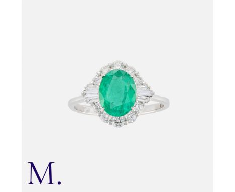 An Emerald And Diamond Cluster Ring in 18k white gold, set with a central oval cut emerald of approximately 1.60cts, within a
