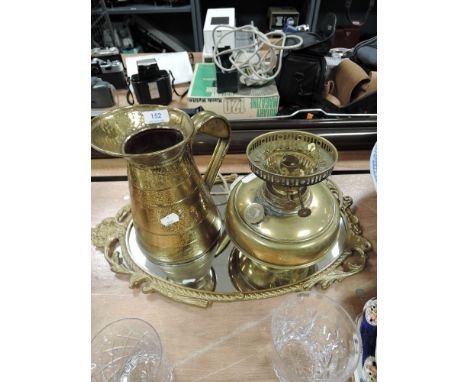 A metal framed hallway mirror a brass oil lamp and a water jug
