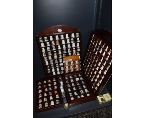 A selection of collectable ceramic and similar thimbles in fitted display cases