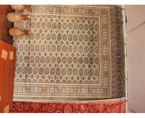A bokhara style carpet with elephant pad motifs on a green field contained by borders. 230x160 