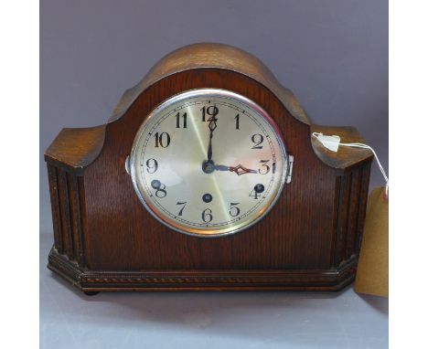 An oak cased Westminster chiming mantle clock, the silvered dial with Arabic numerals and chime/silent lever,  the carved oak