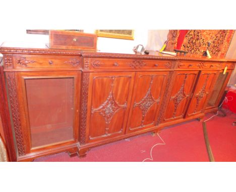 A large chippendale style mahogany breakfront sideboard with four drawers above four carved doors flanked by two glazed doors