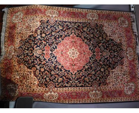 A keshan style carpet with central floral medallion on a blue field contained by repeating borders. 230x160cm 