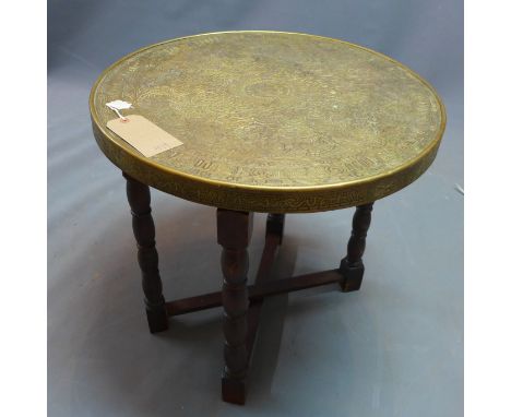 A Middle East brass tray top table, on a carved folding wooden frame, the circular brass top with embossed geometric decorati