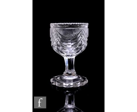 A late Georgian Regency clear cut crystal glass egg cup, the ovoid bowl cut with mitre swags above a slice cut stem and petal