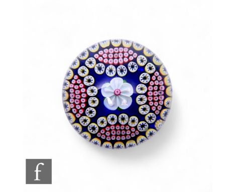 Baccarat - A later 20th Century glass paperweight, of domed form, internally decorated with a stylised lamp work white flower
