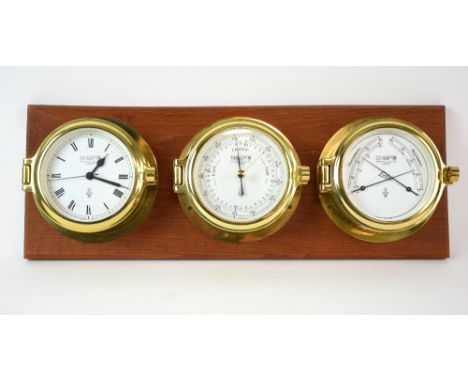 Wempe triple brass ship's barometer, including  a clock and thermometer and hygrometer, mounted on a wooden board, 47 cm wide