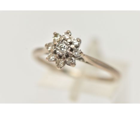 A DIAMOND CLUSTER RING, a round brilliant cut diamond, prong set with a surround of eight single cut diamonds, leading on to 
