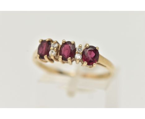 A 9CT GOLD GARNET AND DIAMOND RING, with three oval cut garnets, each four claw set, interspaced with four round brilliant cu