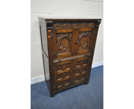 A 20TH CENTURY SOLID OAK DRINKS CABINET, the two double doors , carved with a seated person, an archway and foliate decoratio