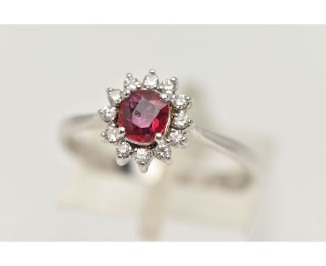 A RUBY AND DIAMOND RING, circular cut ruby prong set in white metal, with a surround of twelve round brilliant cut diamonds, 