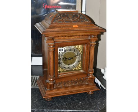 AN EARLY 20TH CENTURY WALNUT CASED CHIMING BRACKET CLOCK, the caddy hood with foliate carved detail, the dial door with three