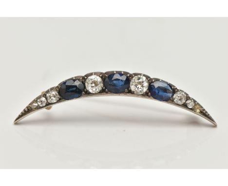 A LATE VICTORIAN DIAMOND AND SAPPHIRE CRESCENT BROOCH, set with three oval cut blue sapphires, interspaced with six old cut d