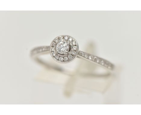 A DIAMOND HALO RING, a single round brilliant cut diamond in a four prong white gold setting, grain set halo surround, leadin