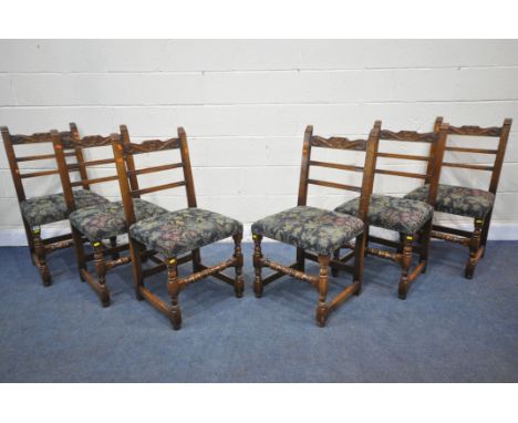 A SET OF SIX REPRODUCTION OAK LADDER BACK DINING CHAIRS, the top rail with scrolled carving, dark blue and floral upholstery,