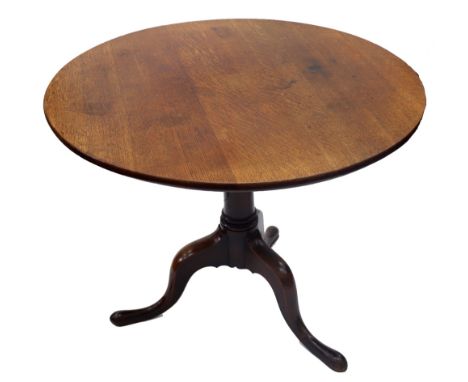 A George III oak tea table, the circular tilt-top on a gun barrel pillar and tripod base, 90cm diameter.