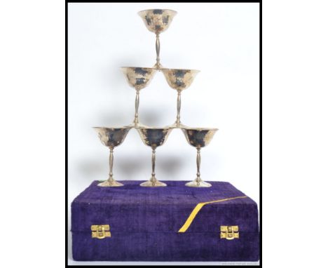 A case of six silver metal wine goblets having a  hand beaten effect presented in a blue velvet case