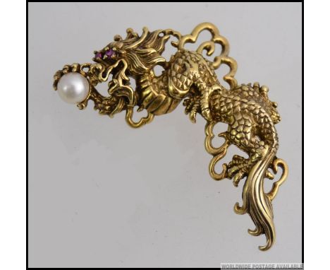 A stunning Chinese gilded silver dragon brooch having freshwater pearl and ruby stone set eyes.