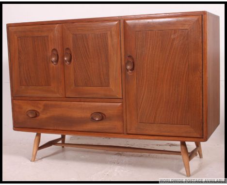 An Ercol Windsor pattern sideboard. Of low form in beech and elm having central bank of drawers with end cupboards. H82 x W11