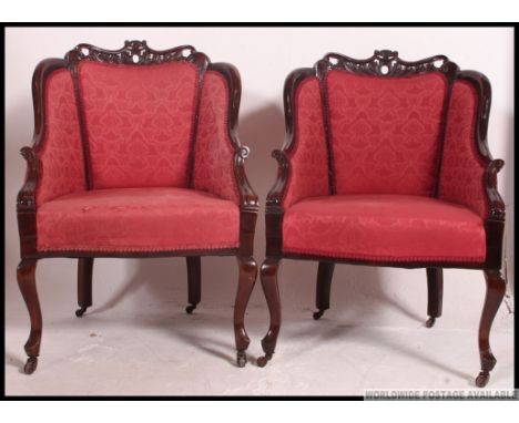 A pair of Edwardian mahogany show wood salon armchairs raised on cabriole legs with rococo carved show wood frames with uphol