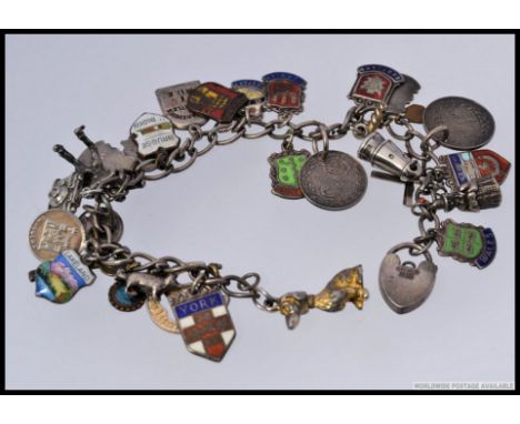 A silver white metal charm bracelet, adorned with various charms, many marked silver