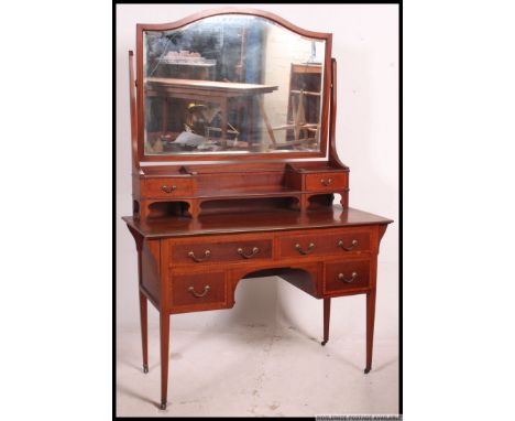 An Edwardian mahogany dressing table being raised on squared legs with a series of drawers and swing mirror atop. Matching bo