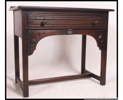 An Ercol Old colonial dark beech and elm wood side table / writing desk. Raised on squared legs with central frieze drawers a