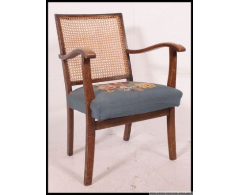 A 1930's mahogany and caned bergere library chair. Raised on cabriole legs with blue tapestry feet having shaped elbow rests 