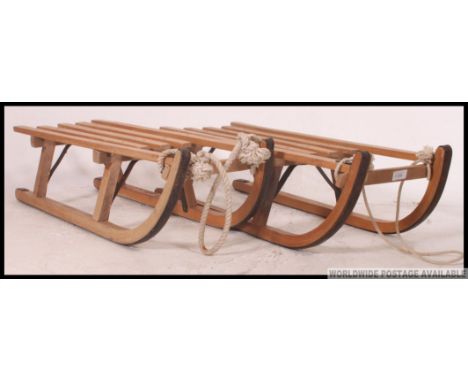 A pair of vintage mid century wooden sledges having slatted seats and ropes in excellent condition. 99cm long.