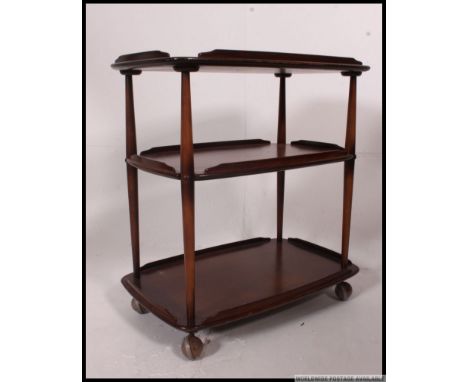 An Ercol Windsor dark elm and beech three tier trolley, on wheels, 72cm wide, 74cm high, 47cm deep. H7 x W72 x D46cm 