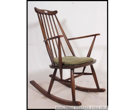 An dark Ercol beech and elm rocking windsor chair  with spindle back being raised on turned legs united by stretchers on runn