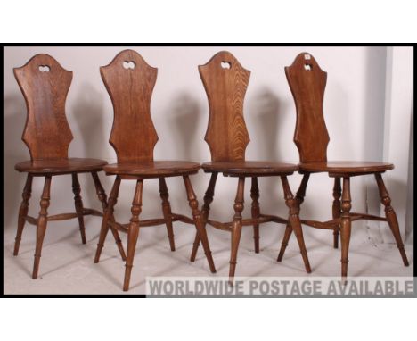 A set of four vintage oak waisted panel back chairs with circular seat pad raised on turned legs united by stretchers