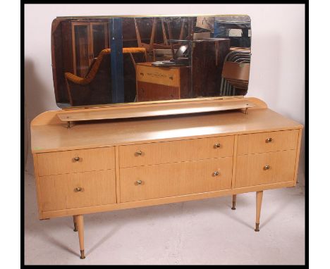 A retro 1970's light wood dressing table chest of drawers. Raised on turned legs with a series of drawers having mirror atop.