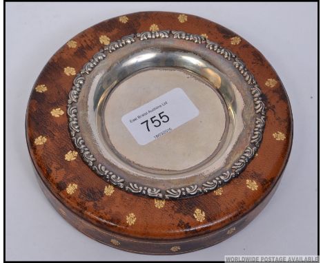 A continental silver wine coaster having marks to the verso set within a leather base with gilt fleur de lys decoration. D14c