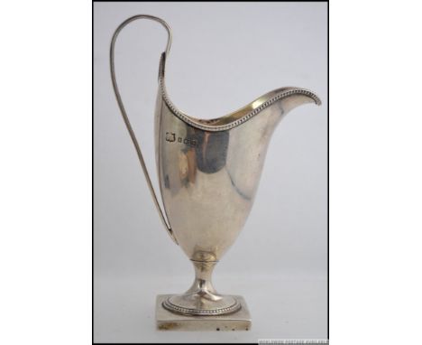 A silver hallmarked jug raised on plinth with scrolled handle bearing hallmarks for Birmingham, date letter K, makers illegib