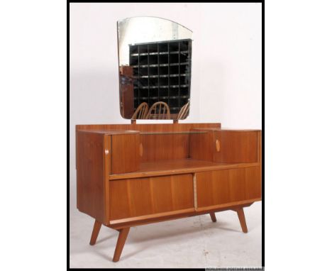 A retro 1960's teak dressing table chest being raised on angled legs with drawers and unusual upper curved door trinket drawe